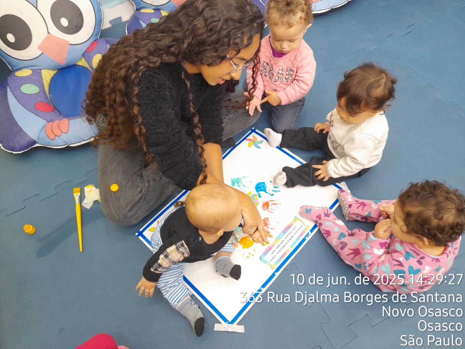 Educadora e bebês em atividade de pintura com as mãos